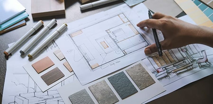 Hands arranging fabric swatches over a floor plan